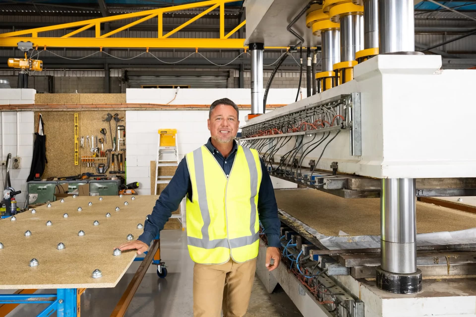 Hydraulic board press with staff compounding hemp into bio-boards